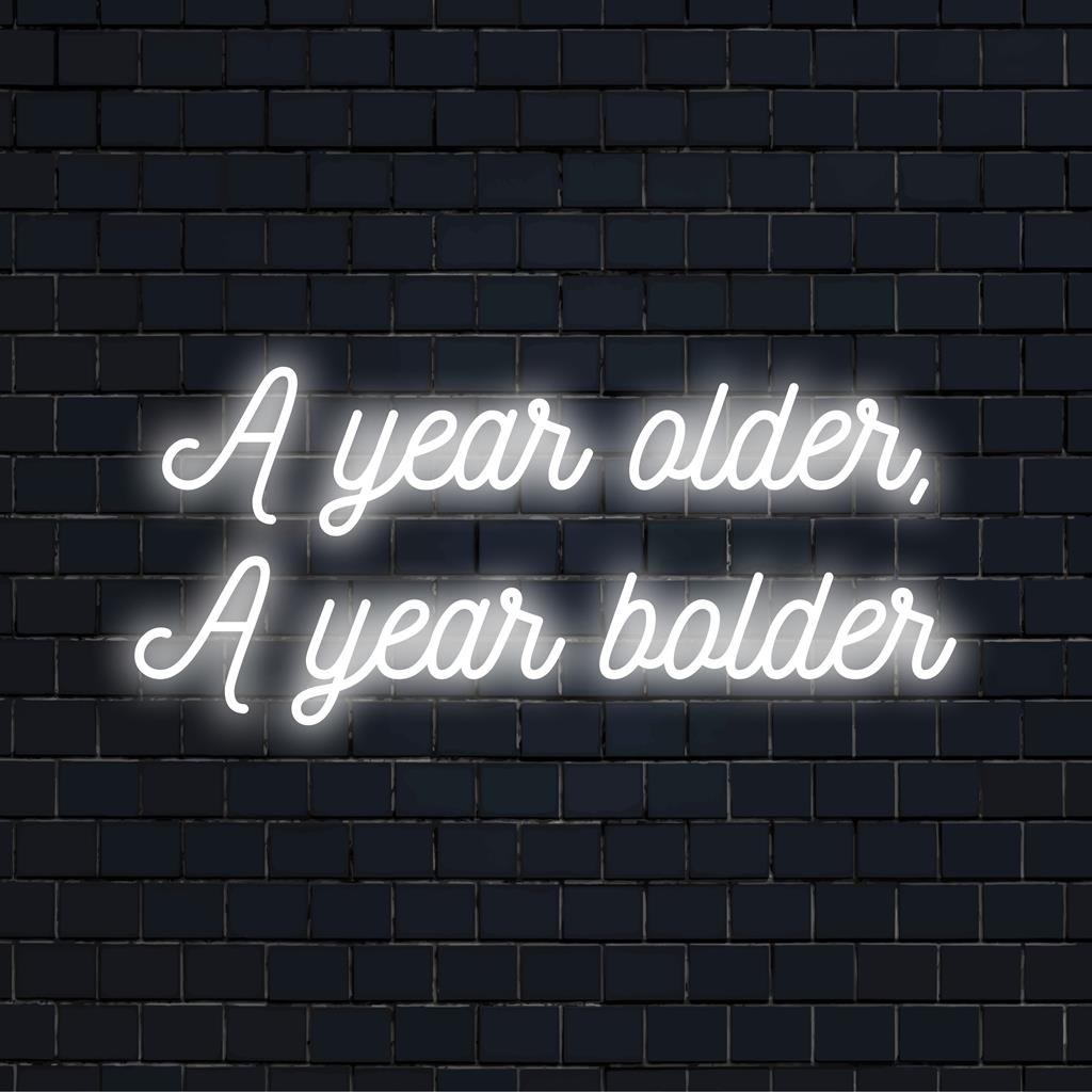 Letreiro de neon LED vibrante com os dizeres "A Year Older, A Year Bolder" como uma impressionante arte de parede neon e decoração de luz personalizada.