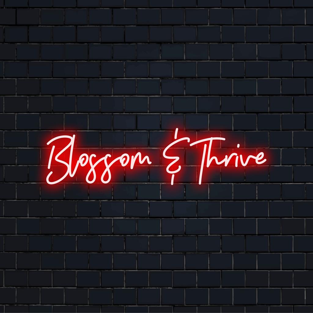 Placa de neon LED com a frase "Blossom And Thrive" em cores vibrantes, perfeita para decoração e arte neon inspiradoras.