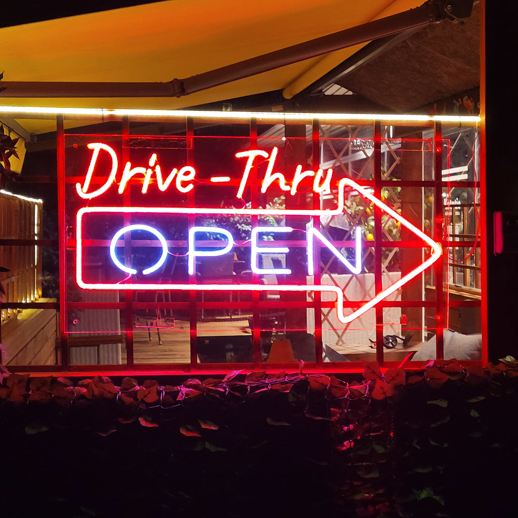 O "Drive Thru Open Neonkyltti" brilha intensamente, convidando os clientes a aproveitar a conveniência do serviço drive-thru.
