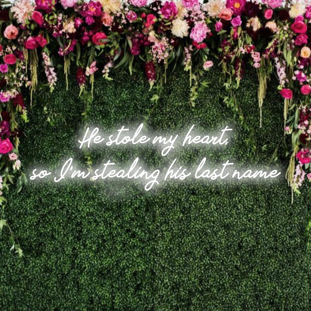 Placa de LED neon personalizada com os dizeres "Ele roubou meu coração, então estou roubando seu sobrenome" em decoração com luzes neon brilhantes.
