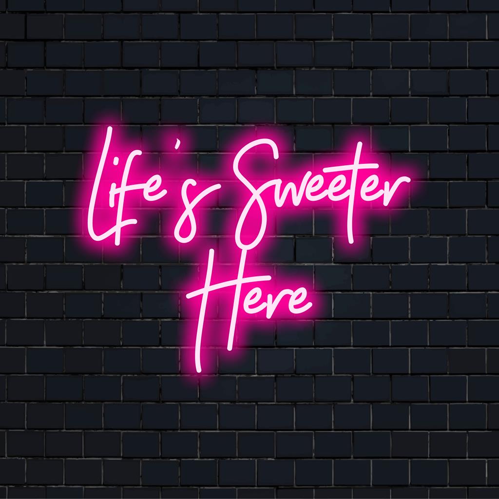 Letreiro de neon LED vibrante com a frase "A vida é mais doce aqui", perfeito para realçar qualquer espaço com um charme de luz neon personalizado.