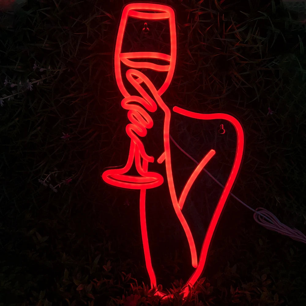 A imagem mostra um letreiro de LED neon vibrante representando o contorno de uma mulher segurando uma taça de vinho.