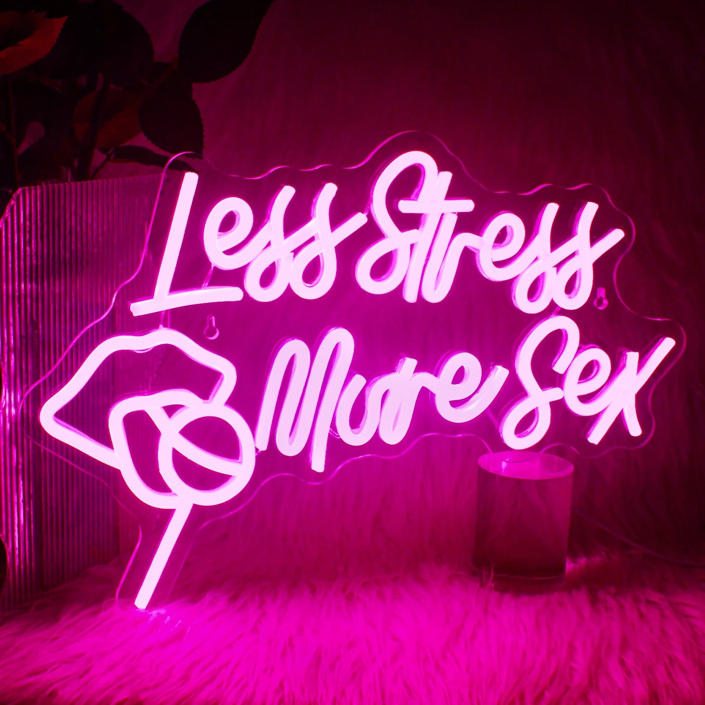 Uma vibrante placa de LED neon exibindo a frase "Menos estresse, mais sexo" em uma fonte cursiva e estilosa.