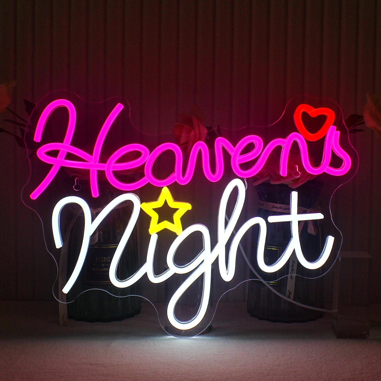 A imagem apresenta uma placa de LED neon feita à mão exibindo as palavras 'Heavens Night' em letras cursivas elegantes.