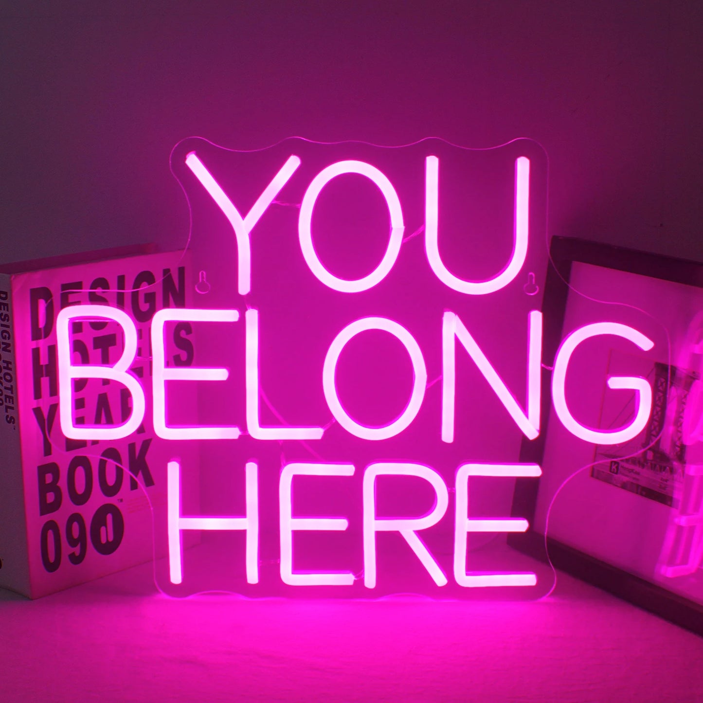 Uma vibrante placa de LED neon exibindo as palavras "You Belong Here" em uma fonte acolhedora e convidativa.