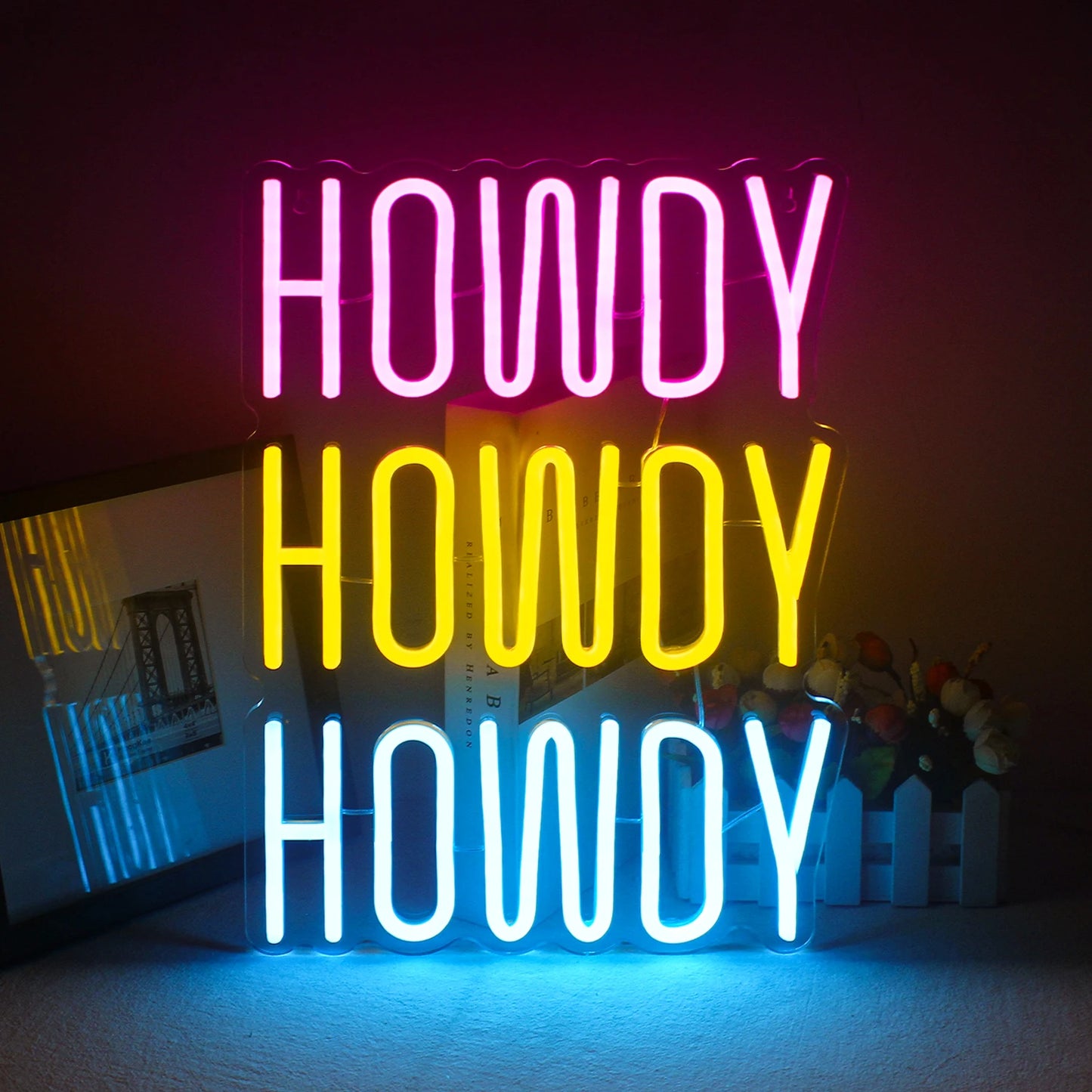 Uma vibrante placa de LED neon feita à mão exibindo a palavra "Howdy" em uma fonte cursiva divertida.