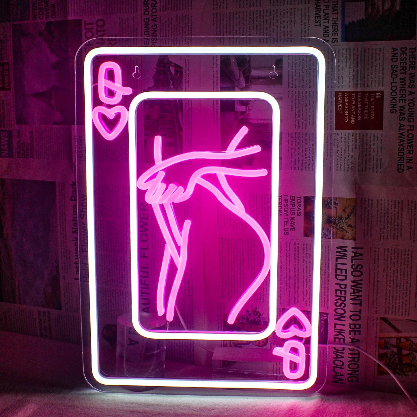 A imagem apresenta um letreiro de neon LED representando uma mulher estilizada, composta por elementos de cartas de baralho.