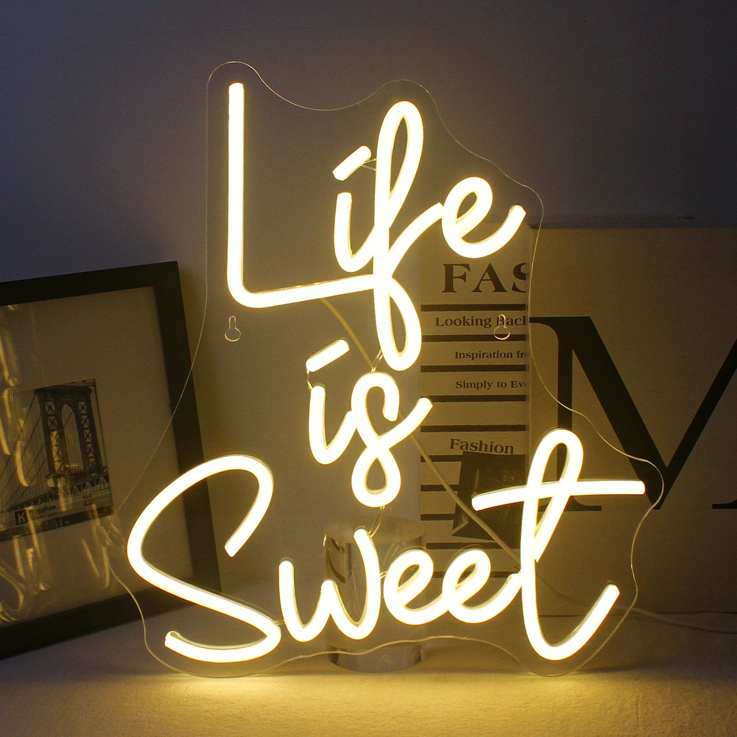A imagem apresenta um letreiro de LED neon vibrante, feito à mão, em cores brilhantes e luminosas, que diz a frase "A vida é doce".