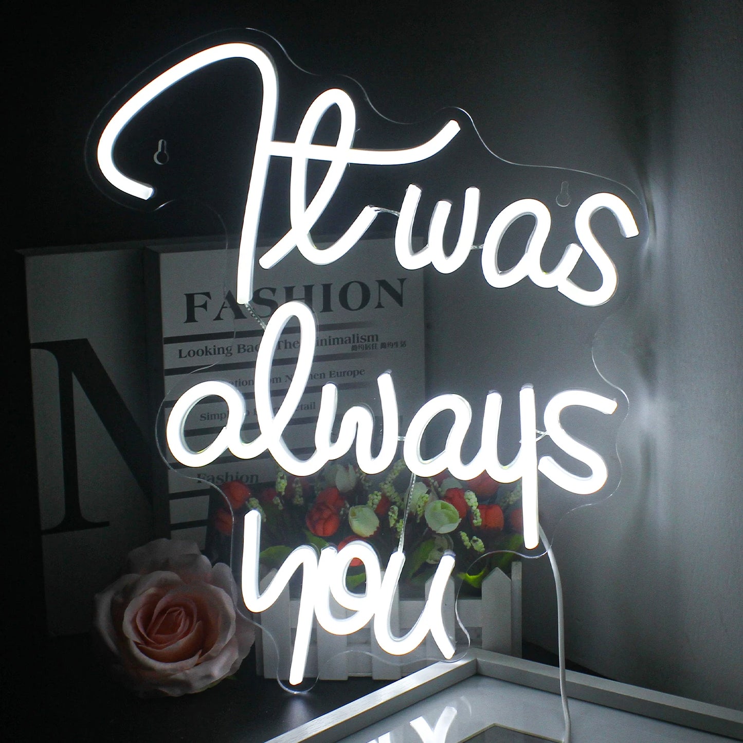 A imagem apresenta uma placa de LED neon feita à mão exibindo as palavras "It Was Always You" em uma letra cursiva elegante.