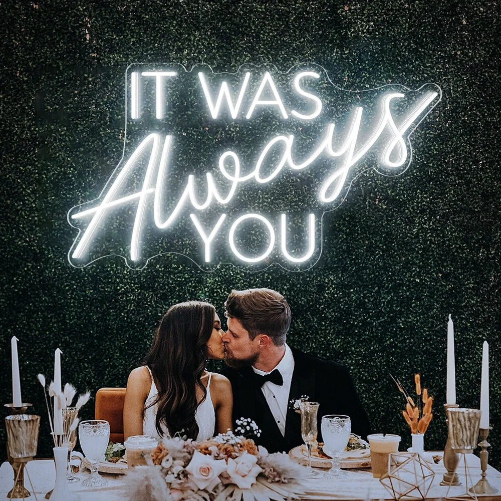 A imagem apresenta uma placa de LED neon feita à mão exibindo a frase "It Was Always You" em uma escrita elegante e fluida.