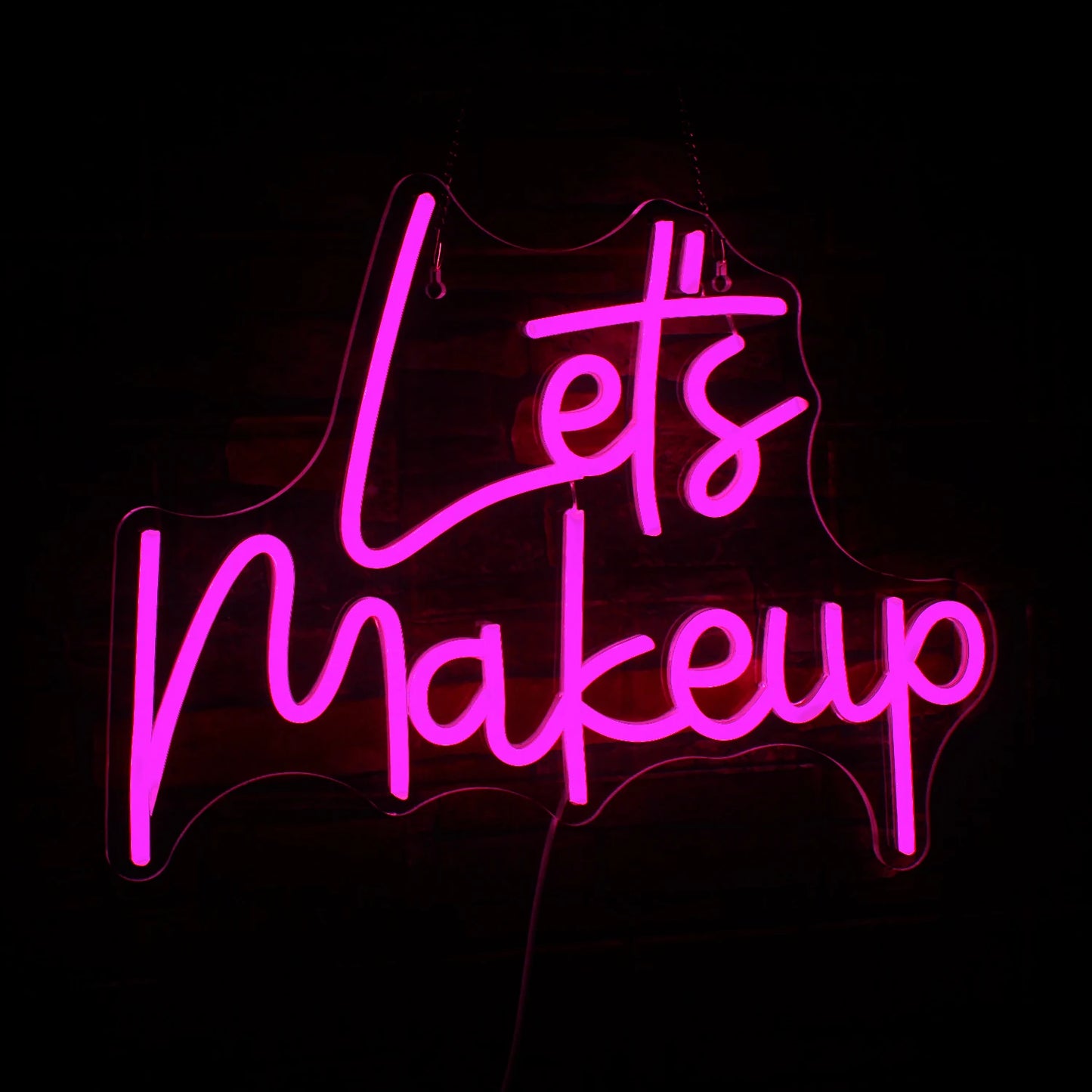 Um elegante letreiro de LED neon exibindo a frase "Let's Makeup" em letras cursivas rosa vibrantes.