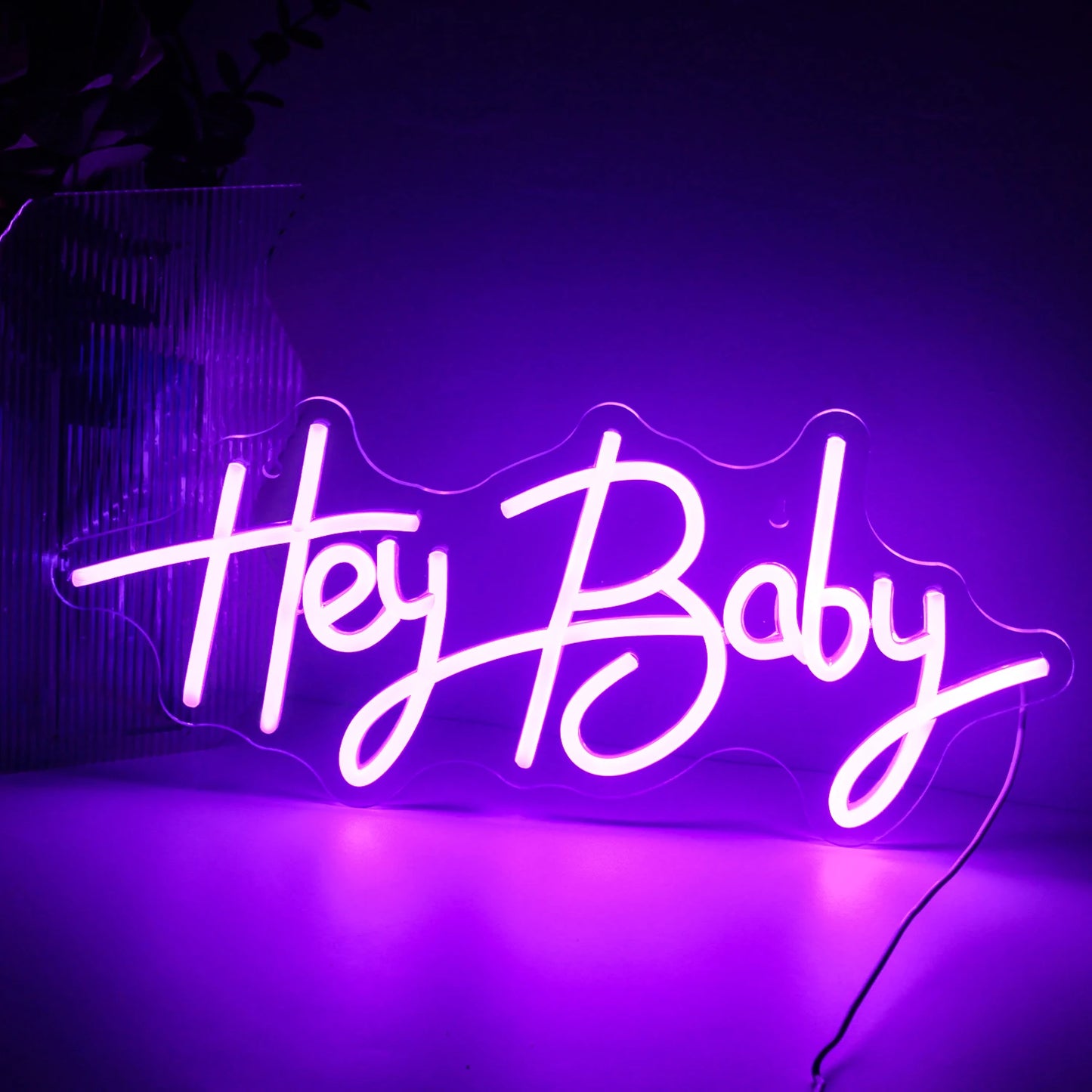 A imagem exibe uma vibrante placa de LED neon feita à mão que diz "Hey Baby" em uma fonte cursiva divertida.