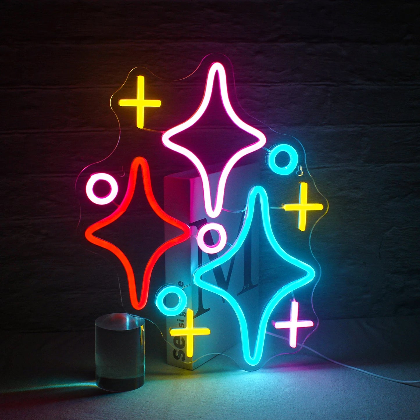 A imagem apresenta um letreiro de LED neon vibrante no formato de um aglomerado de estrelas.