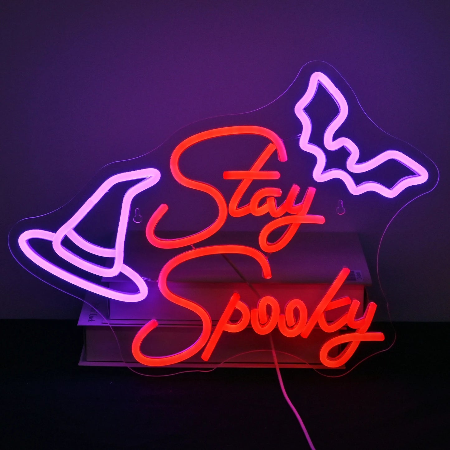 A imagem apresenta uma placa de LED neon feita à mão exibindo as palavras "Stay Spooky" em uma escrita divertida e fluida.