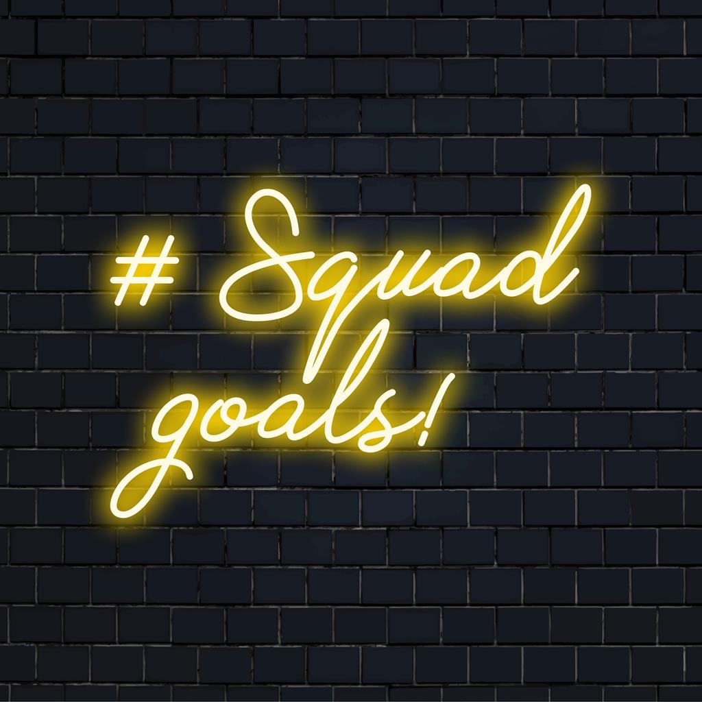 Placa de LED neon personalizada com a frase "#Squad Goals!" em cores vibrantes, ideal para dar um toque moderno a qualquer espaço.