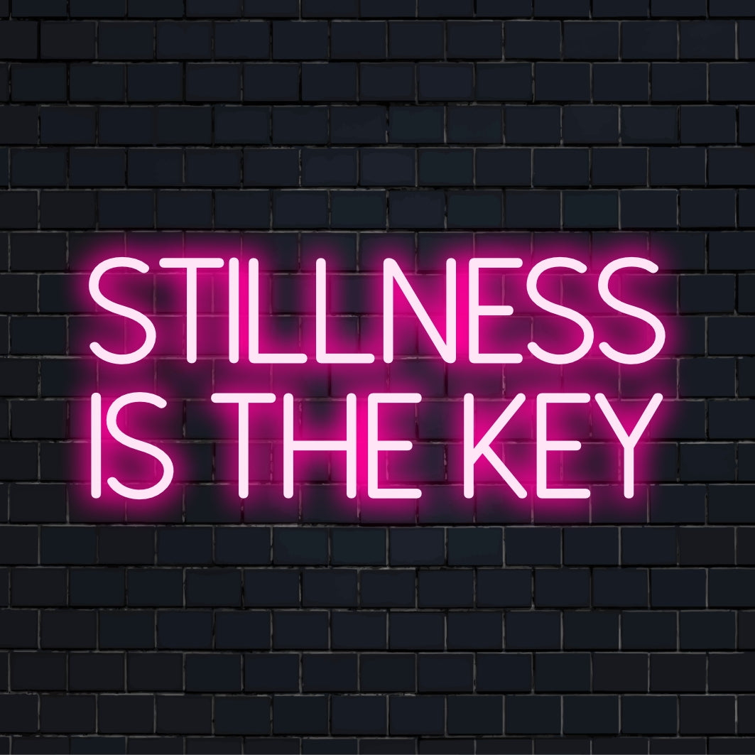 Placa de neon LED personalizada exibindo as palavras "Stillness Is the Key" (A quietude é a chave), perfeita para arte de parede neon personalizada ou decoração inspiradora.