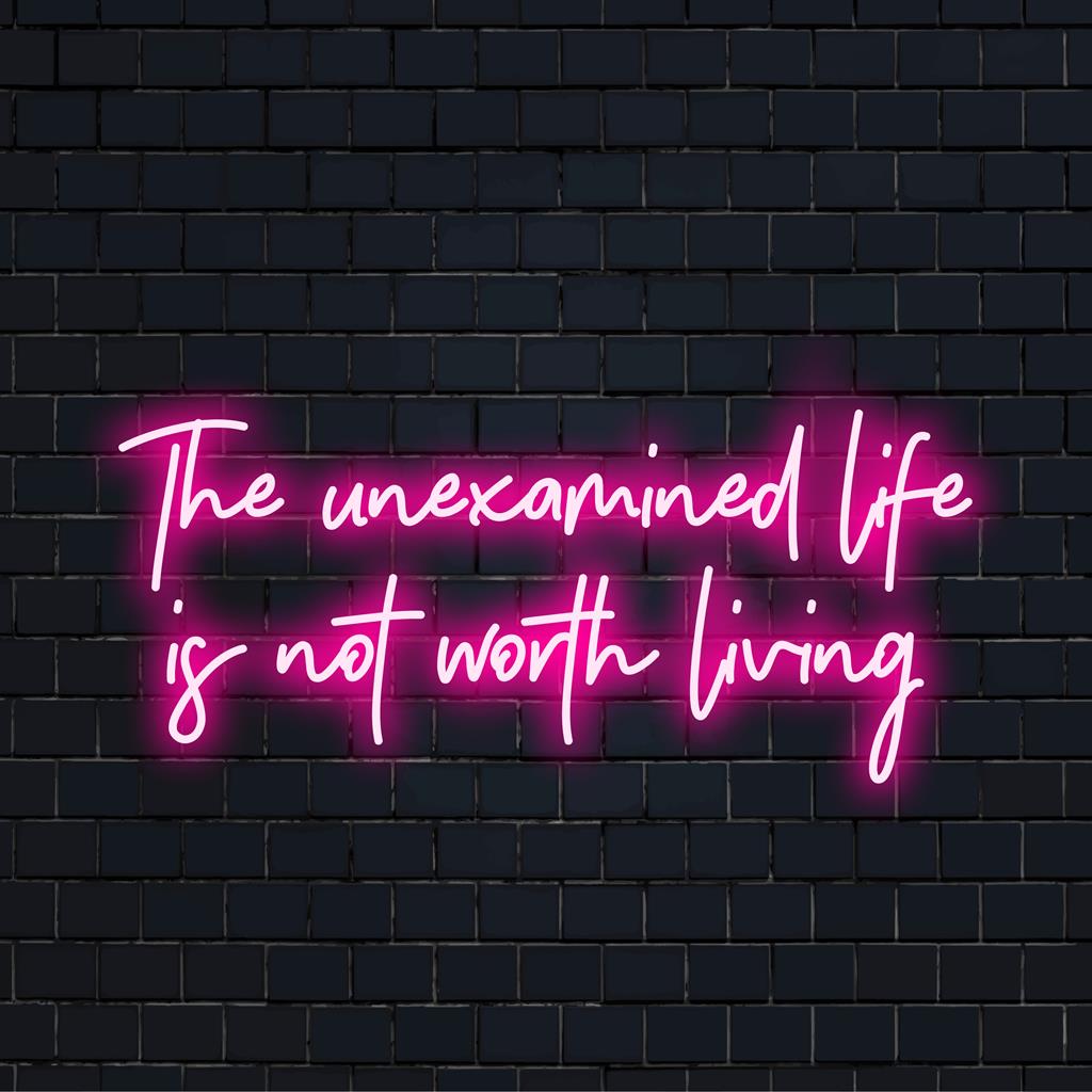 Placa de neon LED com a frase "A vida não examinada não vale a pena ser vivida" em tons vibrantes, perfeita para uma decoração instigante.