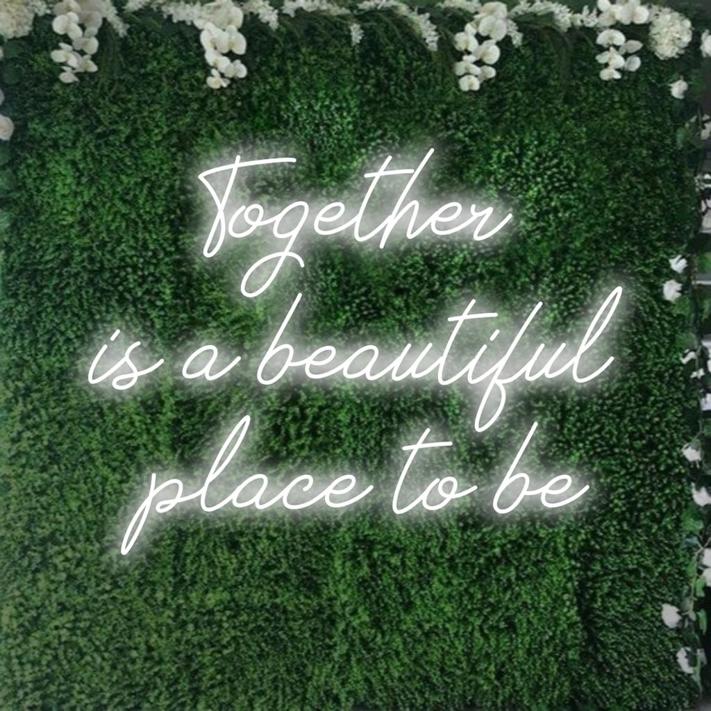 Uma placa de LED neon feita sob medida com a frase Together Is A Beautiful Place To Be brilhando em tons vibrantes, perfeita para decoração de casa.