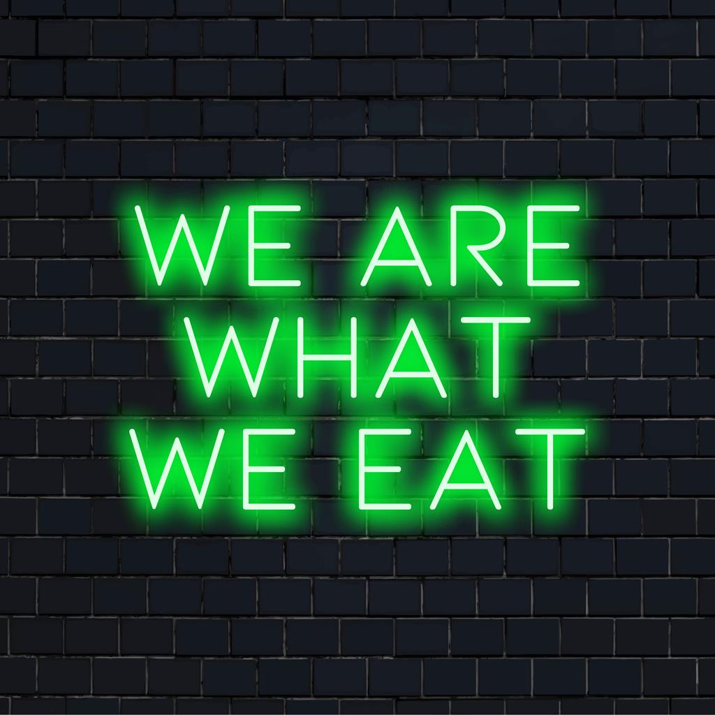 Placa de LED neon com a frase "We Are What We Eat" (Nós somos o que comemos), exibindo arte com luzes neon brilhantes e estéticas, perfeita para decoração moderna.