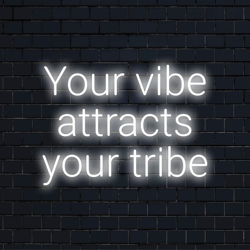 O letreiro de neon vibrante diz "Your Vibe Attracts Your Tribe" em elegantes letras de LED, perfeito para arte de parede e decoração moderna.
