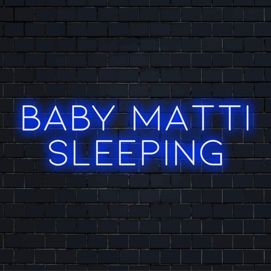 Baby Matti Sleeping Custom Name Neon Sign, glowing lettering on dark brick background
