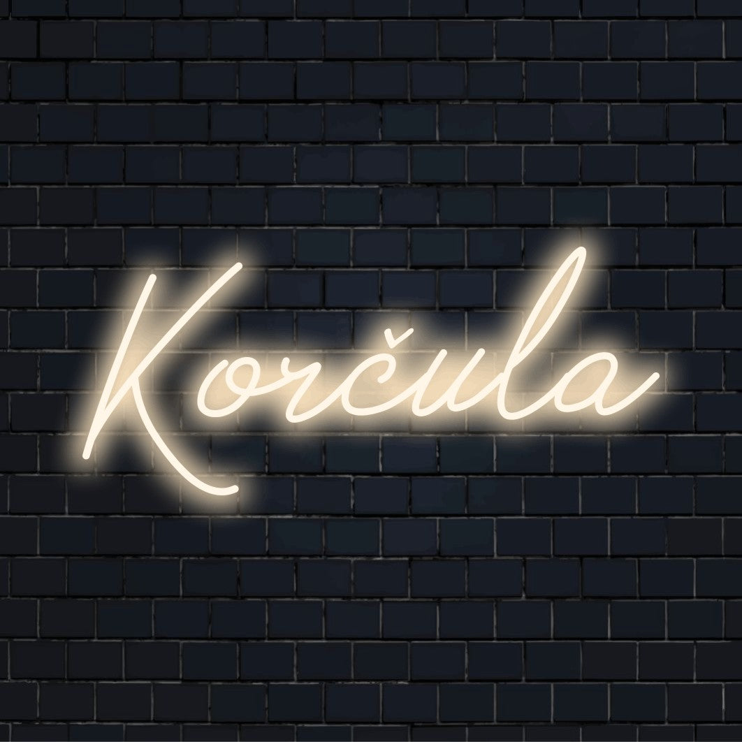 Kor Ula Neon Sign, soft neon glow against black brick wall