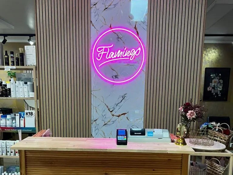 Pink Flamingo logo neon sign installed behind a salon reception desk