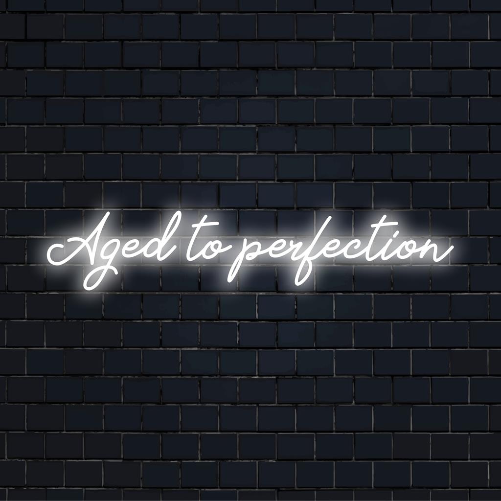 Placa de neon LED exibindo Aged To Perfection em uma escrita elegante, ideal para adicionar um toque personalizado a qualquer espaço.