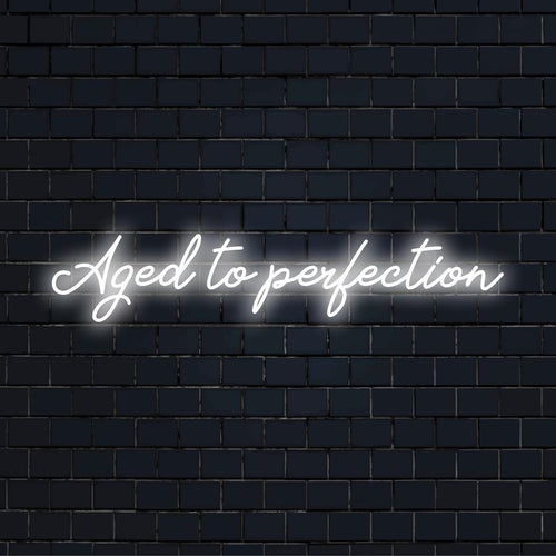 Placa de neon LED exibindo Aged To Perfection em uma escrita elegante, ideal para adicionar um toque personalizado a qualquer espaço.
