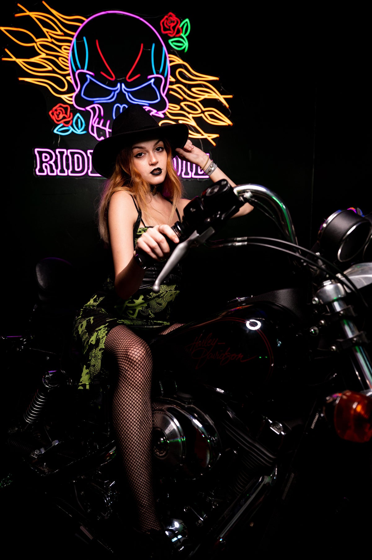Custom biker artwork LED neon sign displayed behind a motorcycle rider
