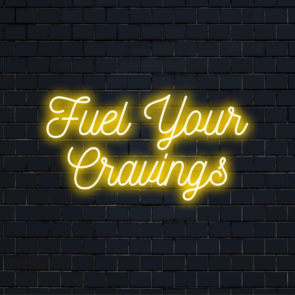 Placa de LED neon personalizada com a frase Fuel Your Cravings, com design tipográfico moderno e cores neon vibrantes.
