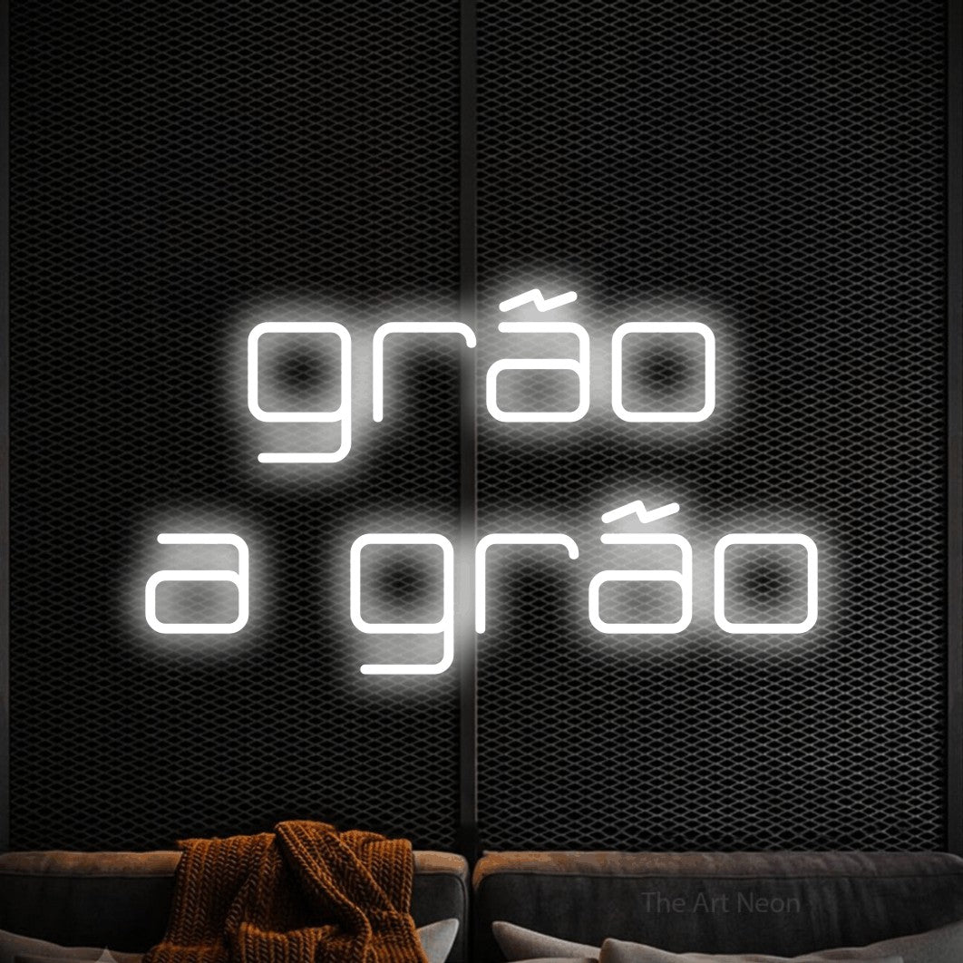 LED neon sign reading “grão a grão”, arranged in 2 lines.