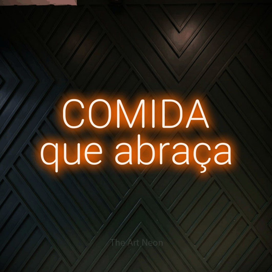 LED neon sign reading “COMIDA que abraça”, arranged in 2 lines.