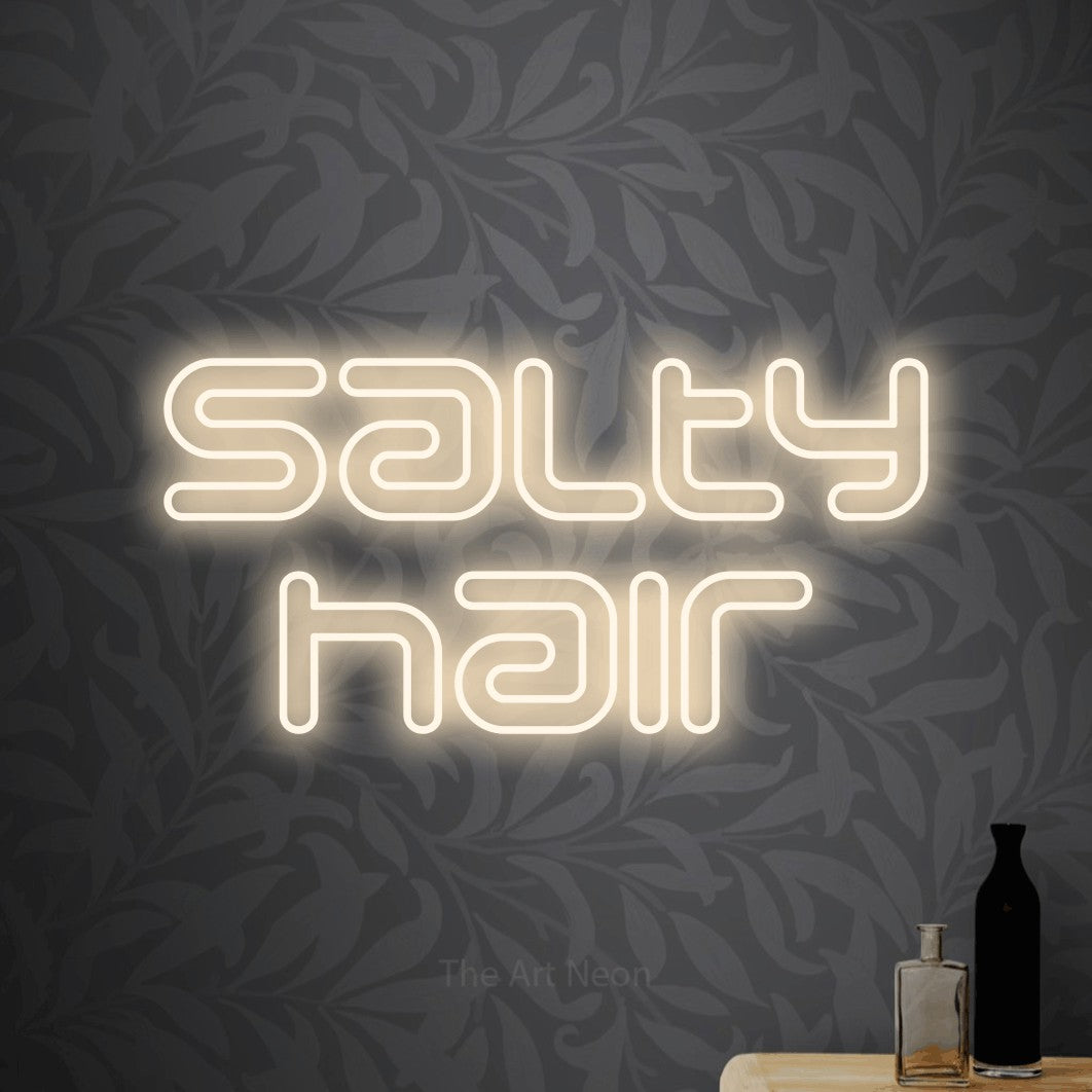 LED neon sign reading “salty hair”, arranged in 2 lines.