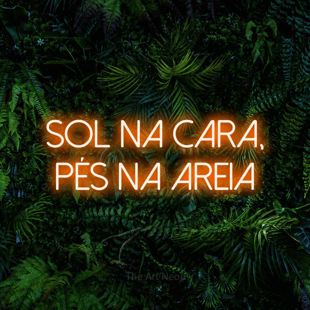 LED neon sign reading “SOL NA CARA, PÉS NA AREIA”, arranged in 2 lines.