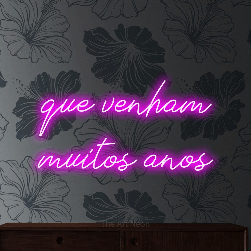 LED neon sign reading “que venham muitos anos”, arranged in 2 lines.