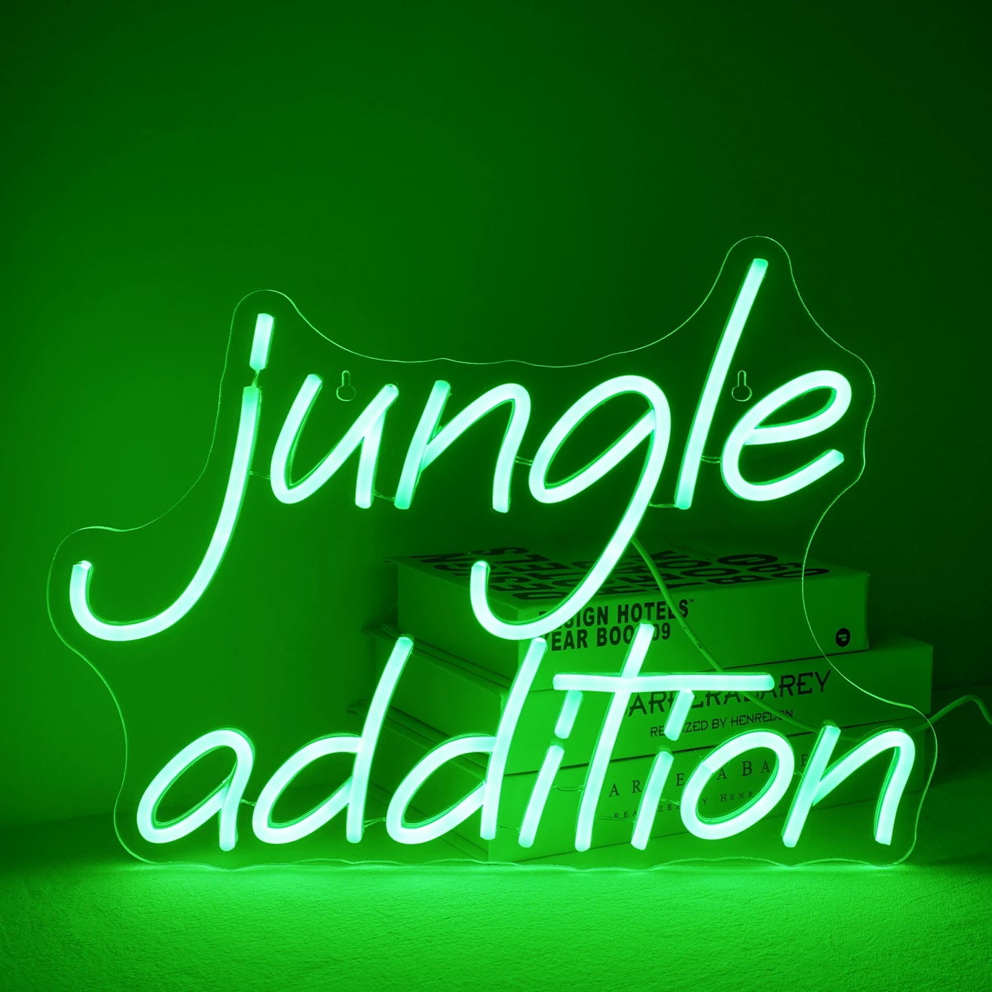 Uma vibrante placa de LED neon verde "Jungle Addition", colocada sobre um fundo de parede branca minimalista.