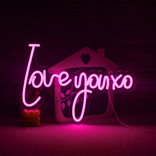 A imagem apresenta uma vibrante e chamativa placa de LED neon feita à mão exibindo a frase "Te amo, XO".