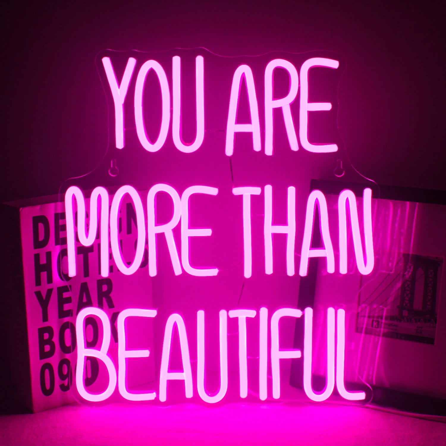 A imagem apresenta um letreiro de LED neon vibrante exibindo a frase "Você é mais que bonita".