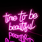 Uma vibrante placa de LED neon com os dizeres "Hora de ser bonita" exibida em uma parede cinza escuro minimalista.