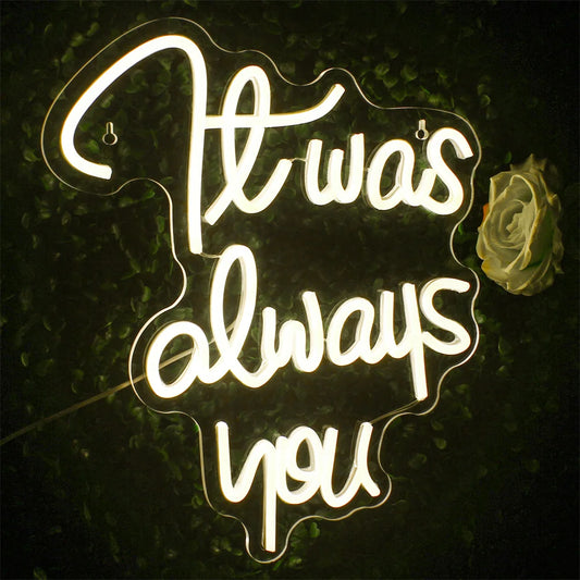 "A vibrant LED neon sign displaying the phrase 'It was always you' in elegant cursive lettering.
