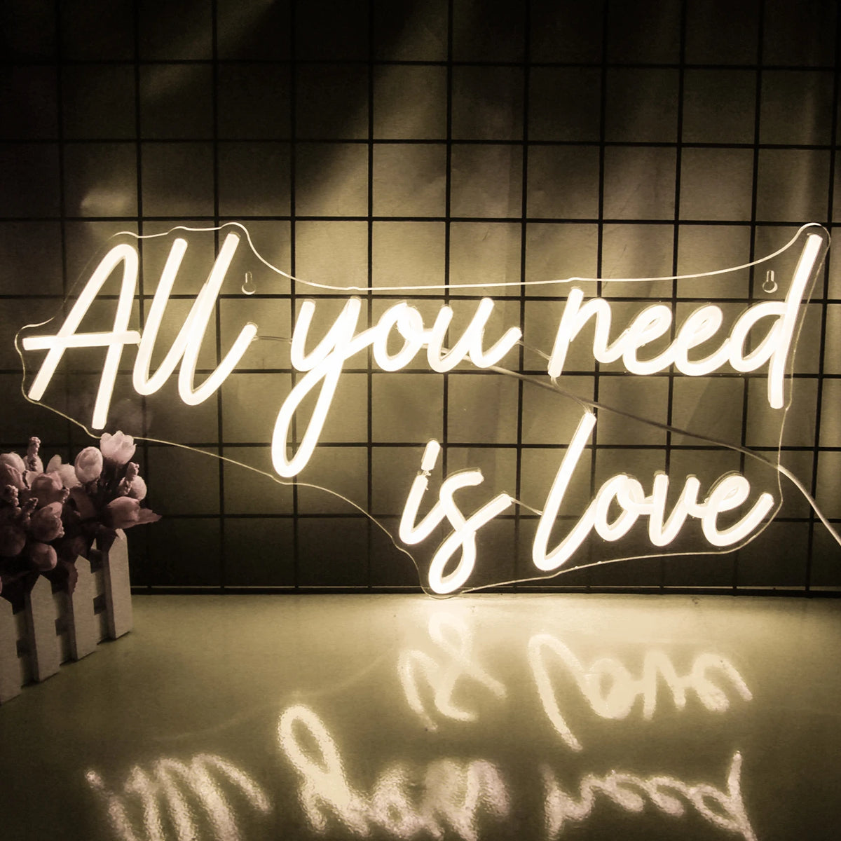 A imagem apresenta uma vibrante placa de LED neon exibindo o texto "You Need Is Love" em letras brilhantes e luminosas.