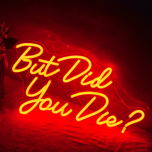 A imagem apresenta um letreiro de LED neon vibrante exibindo a frase "Mas você morreu" em letras grandes e divertidas.