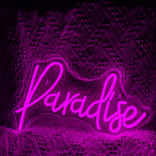 The image displays a vibrant, handmade LED neon sign spelling out the word "Paradise" in a playful cursive font.