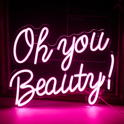 The image features a vibrant, handmade LED neon sign displaying the words "Oh You Beauty.