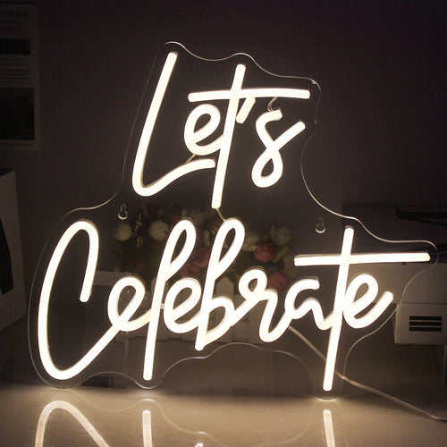A imagem apresenta uma vibrante placa de LED neon com os dizeres "Vamos Celebrar".