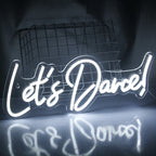 Um letreiro de LED neon brilhantemente iluminado com os dizeres "Vamos Dançar" em cores vibrantes como rosa e azul.