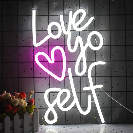 The image displays a vibrant LED neon sign with the words "Love Yourself" illuminated in a stylish script font.