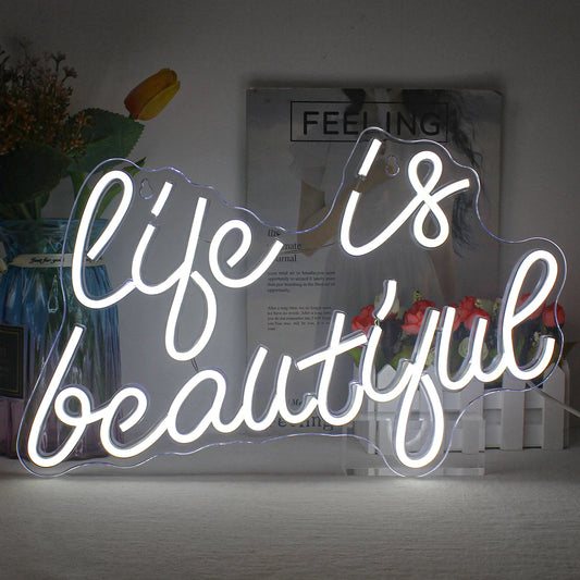 The image features a vibrant, glowing LED neon sign displaying the phrase "Life is Beautiful" in a cursive font.