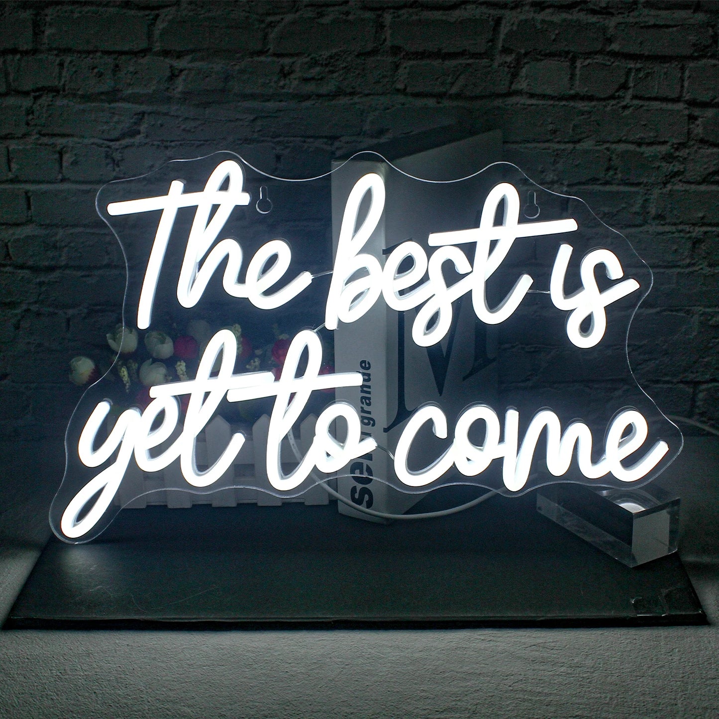The image showcases a vibrant, handmade LED neon sign that reads "The Best is Yet to Come" in a stylish, cursive font.